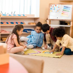 Selective focus of children playing game on floor in montessori school